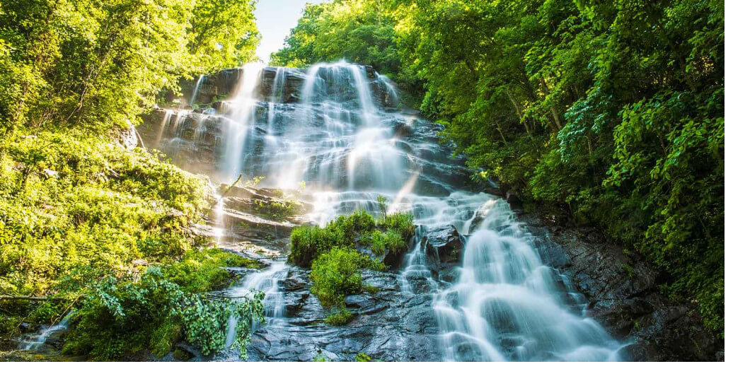 Amicalola Falls cascading over rock ledges through green forest in the North Georgia mountains